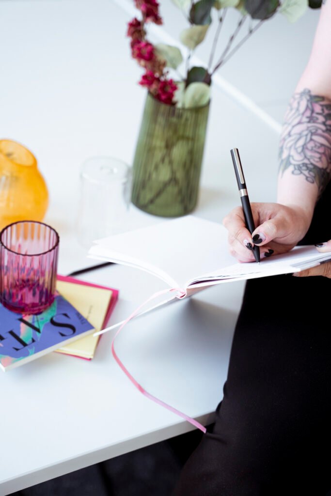 Palvelumuotoilun asiantuntija Inka, kirjoittaa muistiinpanoja värikkäiden esineiden keskellä – edustamassa käyttäjälähtöistä suunnittelua ja tulevaisuuden huomioimista palvelumuotoilussa